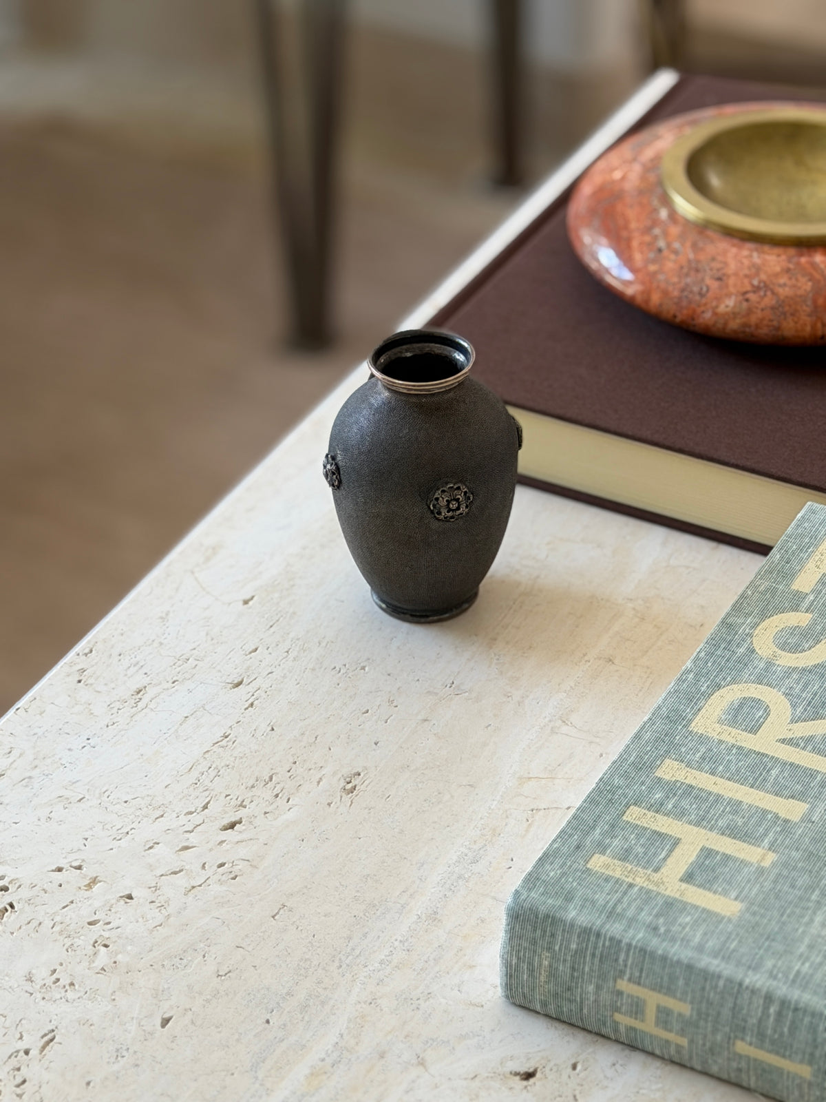 Buccellati vase near a table edge with chair legs blurred in the background