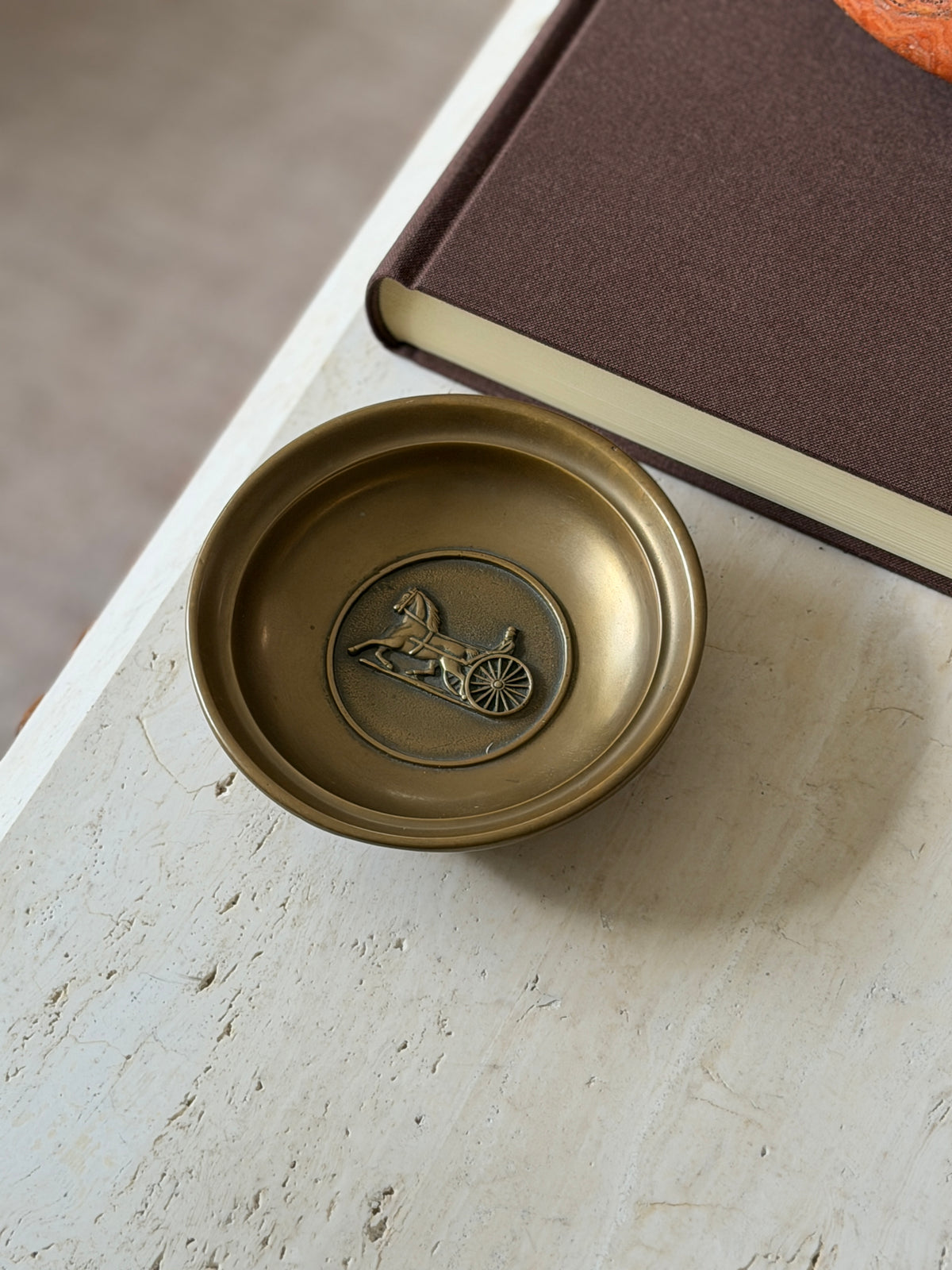 Closer view of the same dish, showing the detail of the horse, driver, and wheel in the medallion