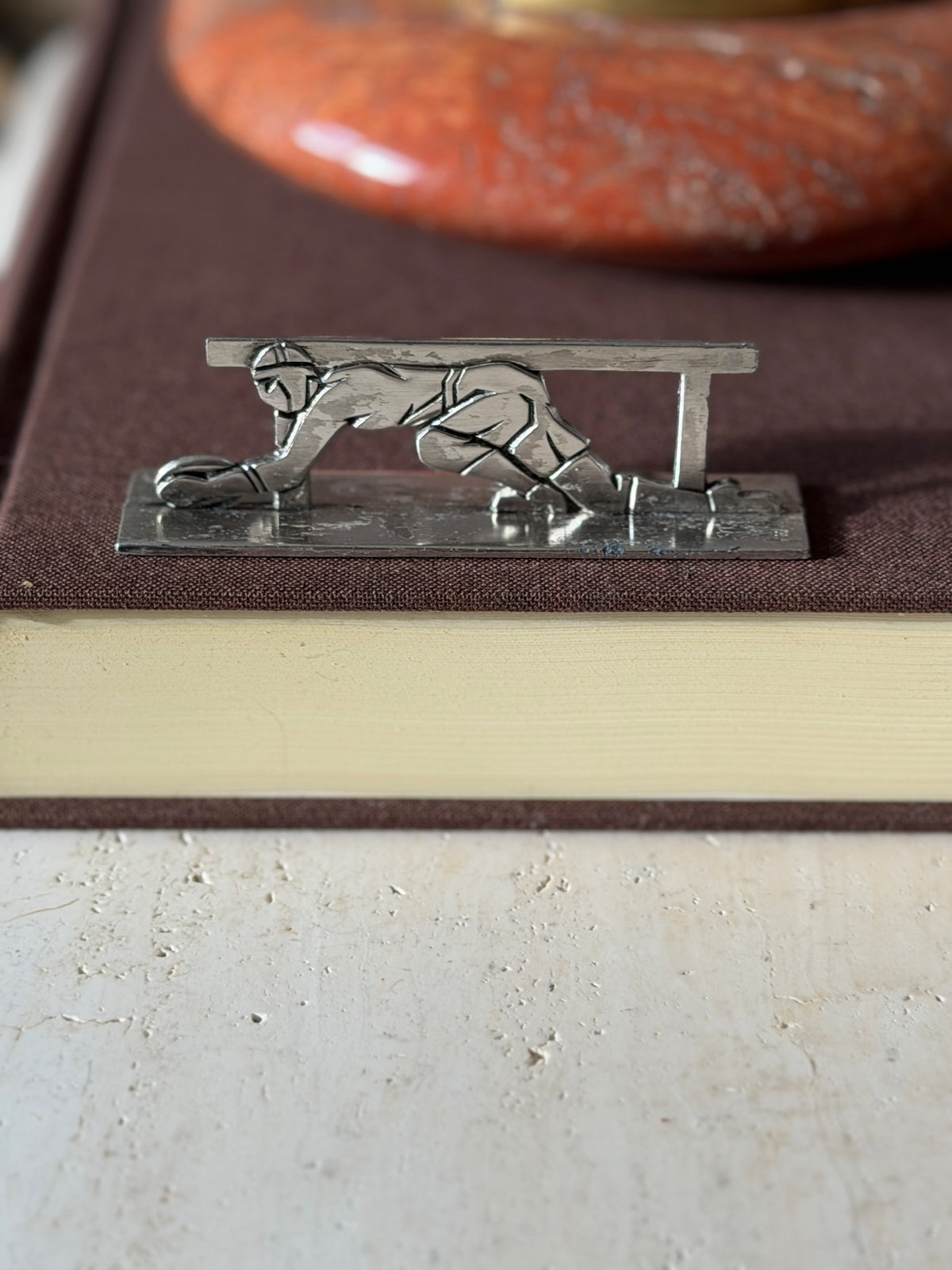 Rugby knife rest on a brown book, a capped player diving to ground the ball beneath the rail