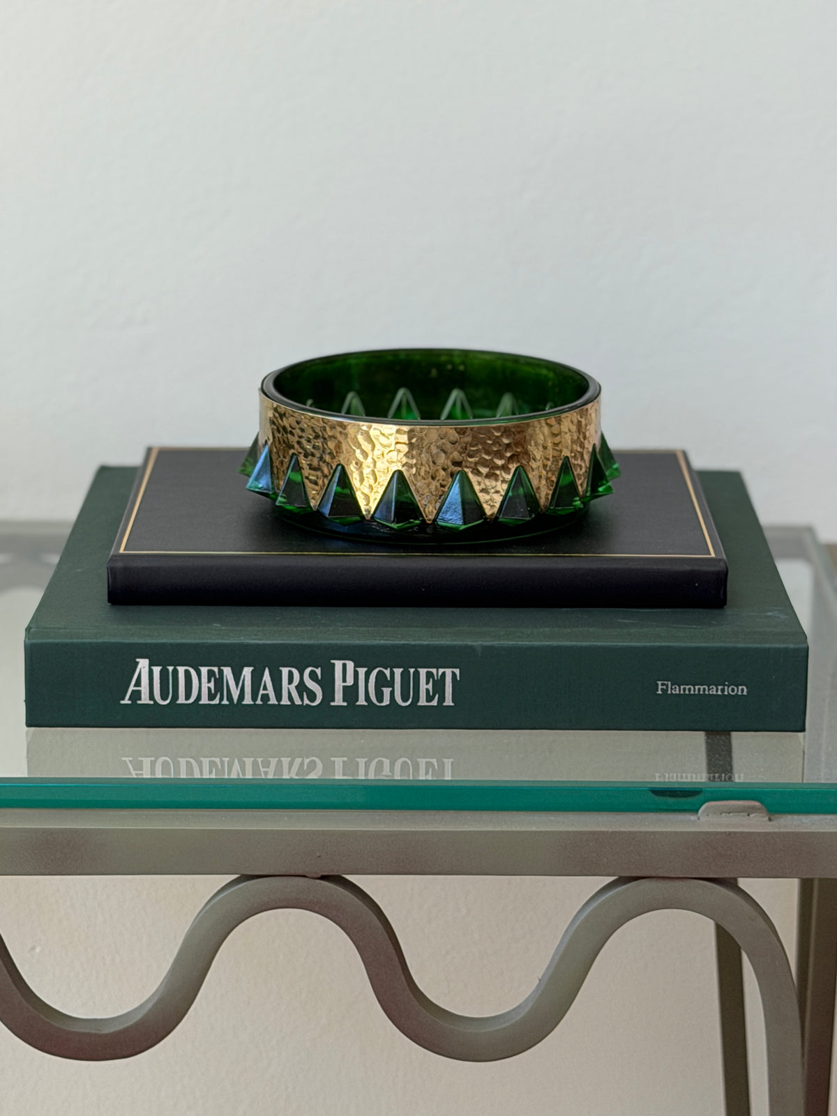 Eye-level side profile view of round green glass and hammered brass decorative bowl tray