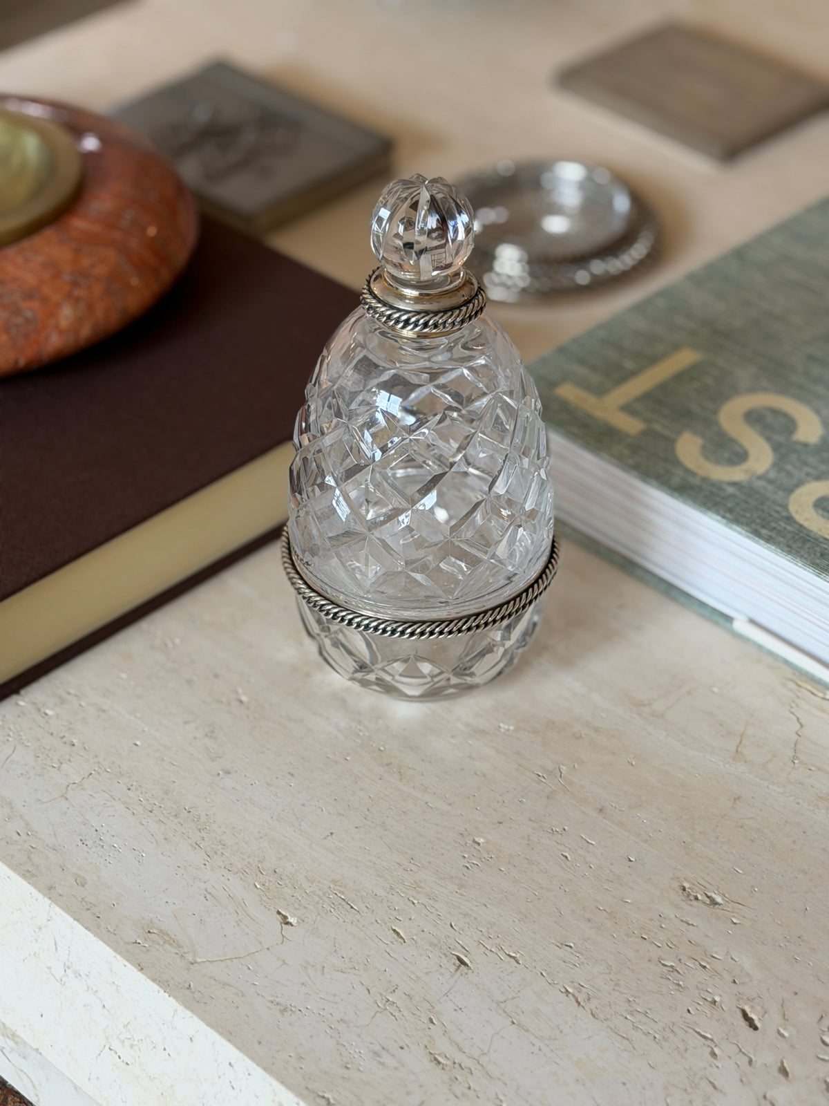 Hermes crystal bottle with a diamond-cut pattern styled beside a marble ashtray