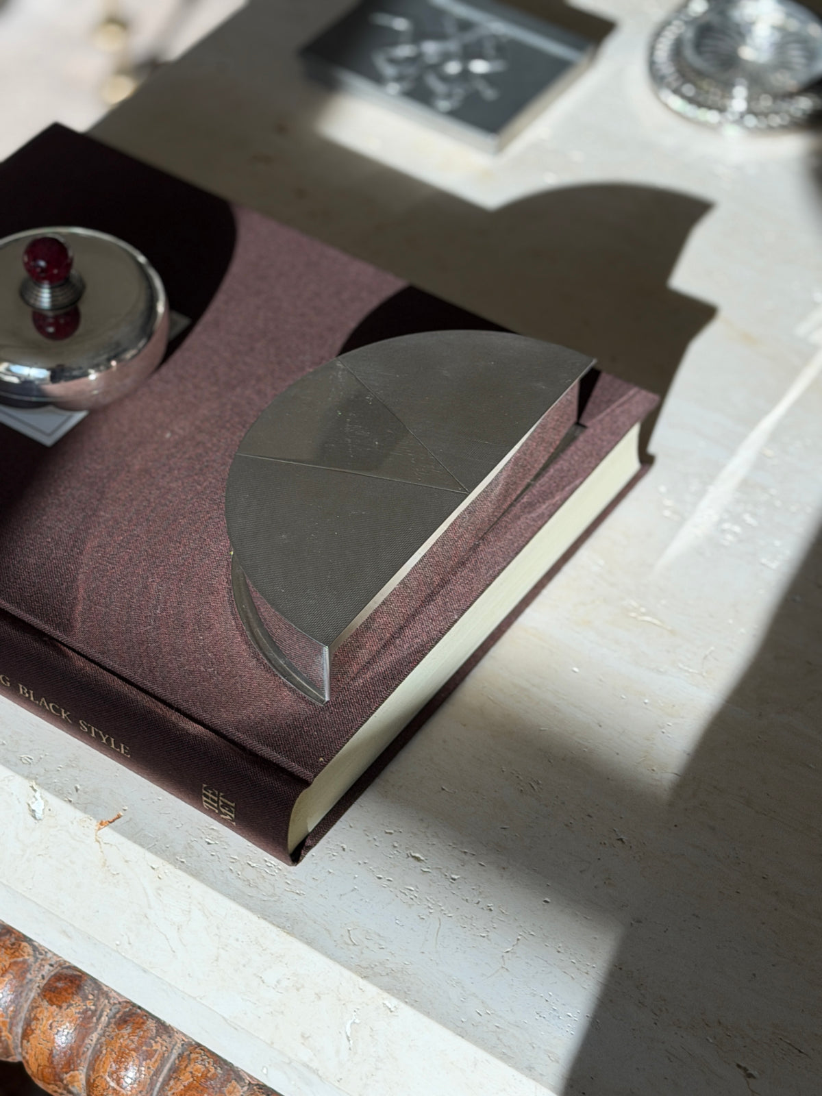 Angled view of the semicircular Olivetti box on the Superfine Tailoring Black Style book, the fan of engine turned panels catching sunlight