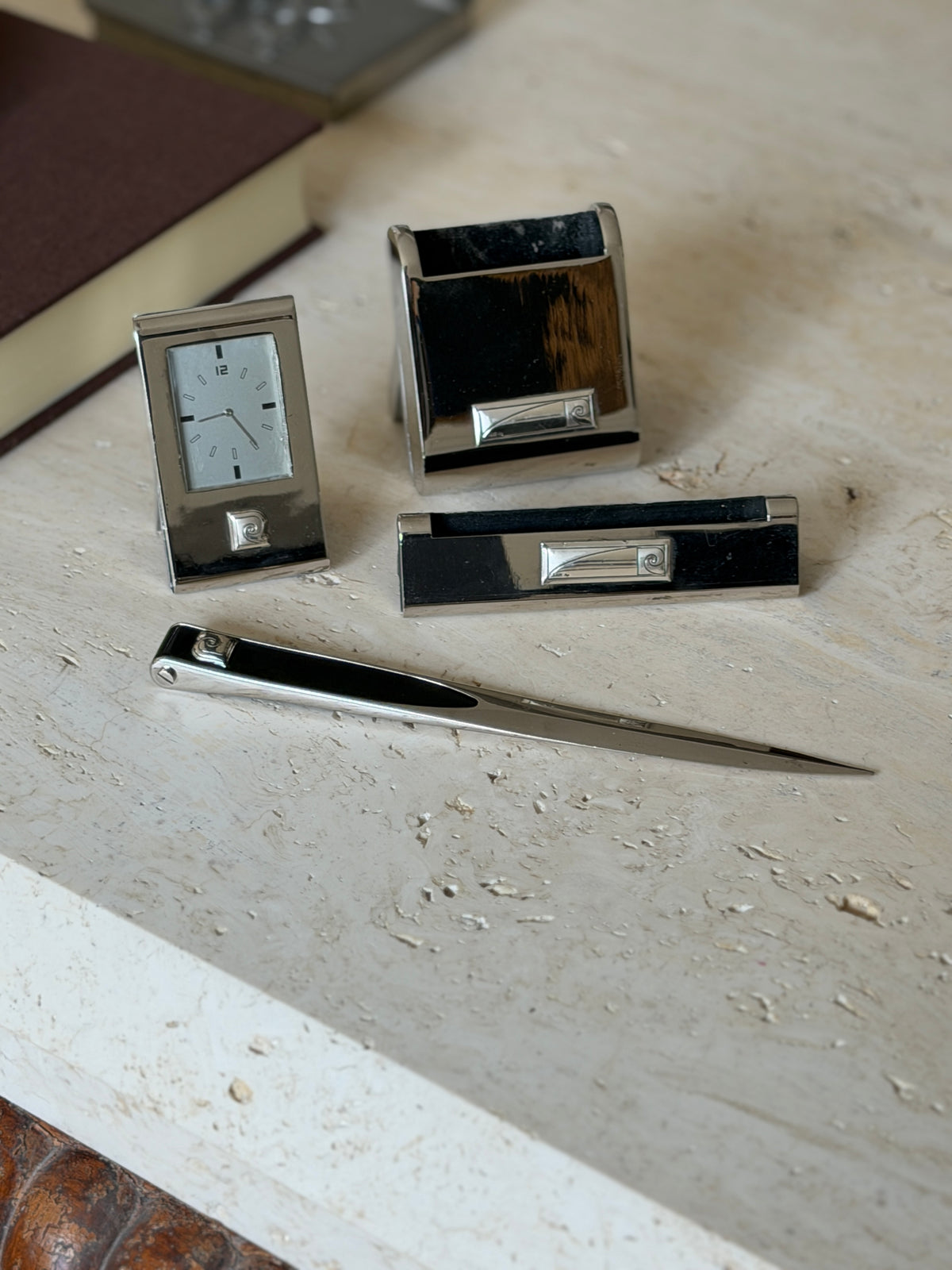 Low angle view of the chrome desk set, the letter opener with black inlaid handle in front of the clock and holders