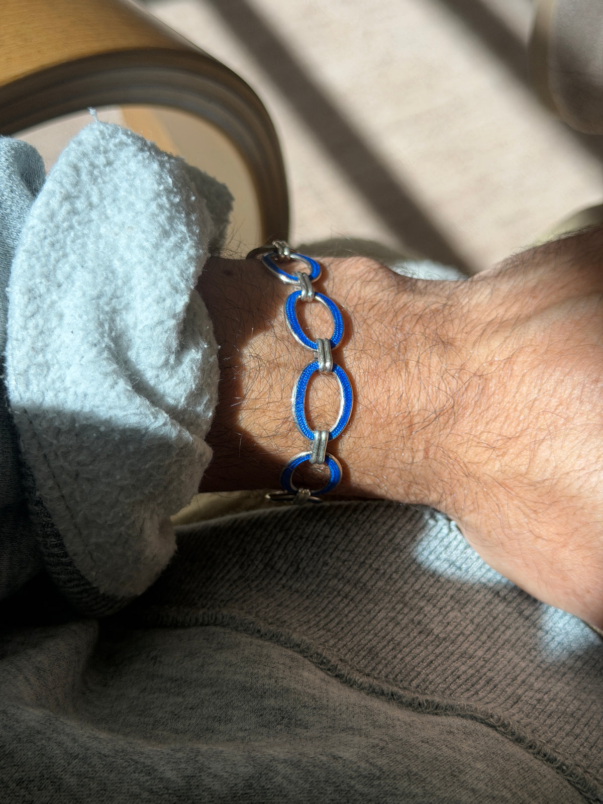 Wrist view of the oval link bracelet in vivid blue enamel, highlighting the grooved double bar links that connect each segment