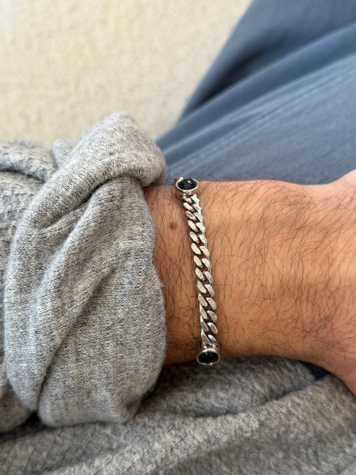 Vintage German sterling silver curb link bracelet with a round black onyx cabochon in a smooth bezel, worn on the wrist against a gray knit sleeve