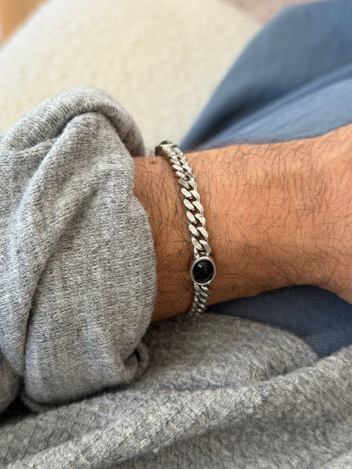 Top view of the onyx curb bracelet on the wrist, two glossy black cabochons framing a run of flat polished curb links
