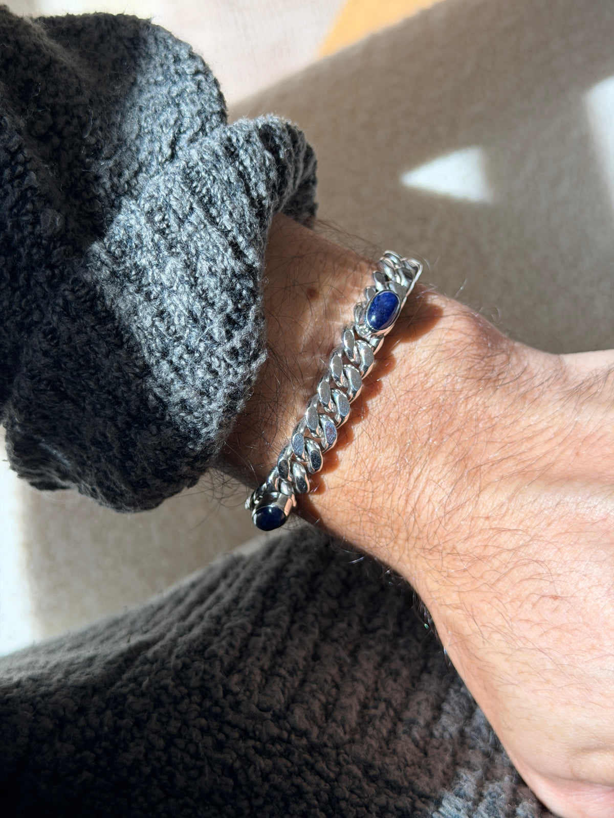 Angled wrist view of the lapis lazuli curb bracelet, a bezel set cabochon framed by the mirror bright chain