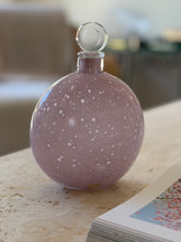 Close view of the lilac Murano decanter showing the dense white speckling across the glass and the maker label near the foot