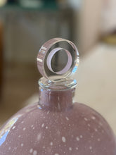 Close up of the Barbini stopper, a thick clear glass disc enclosing a lilac ring with tiny trapped bubbles