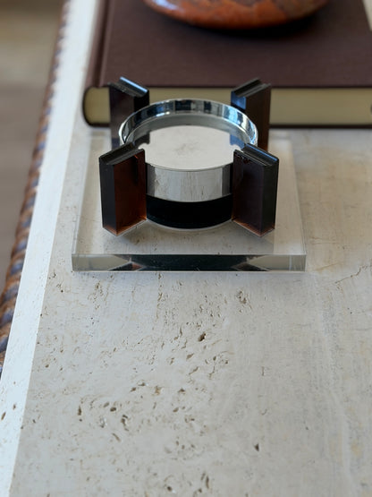 Straight-on view of the 1970s floating ashtray revealing the black magnetic base between two amber uprights and the beveled edge of the square Lucite base
