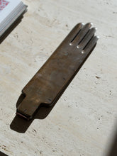 Antique brass industrial glove mold by Pelletier and Jaminet in raking sunlight on travertine, four rounded fingers and a narrow stepped cuff end