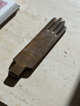 Angled view of the brass glove mold casting a long shadow on travertine, the warm patina and copper toned cuff plate in view