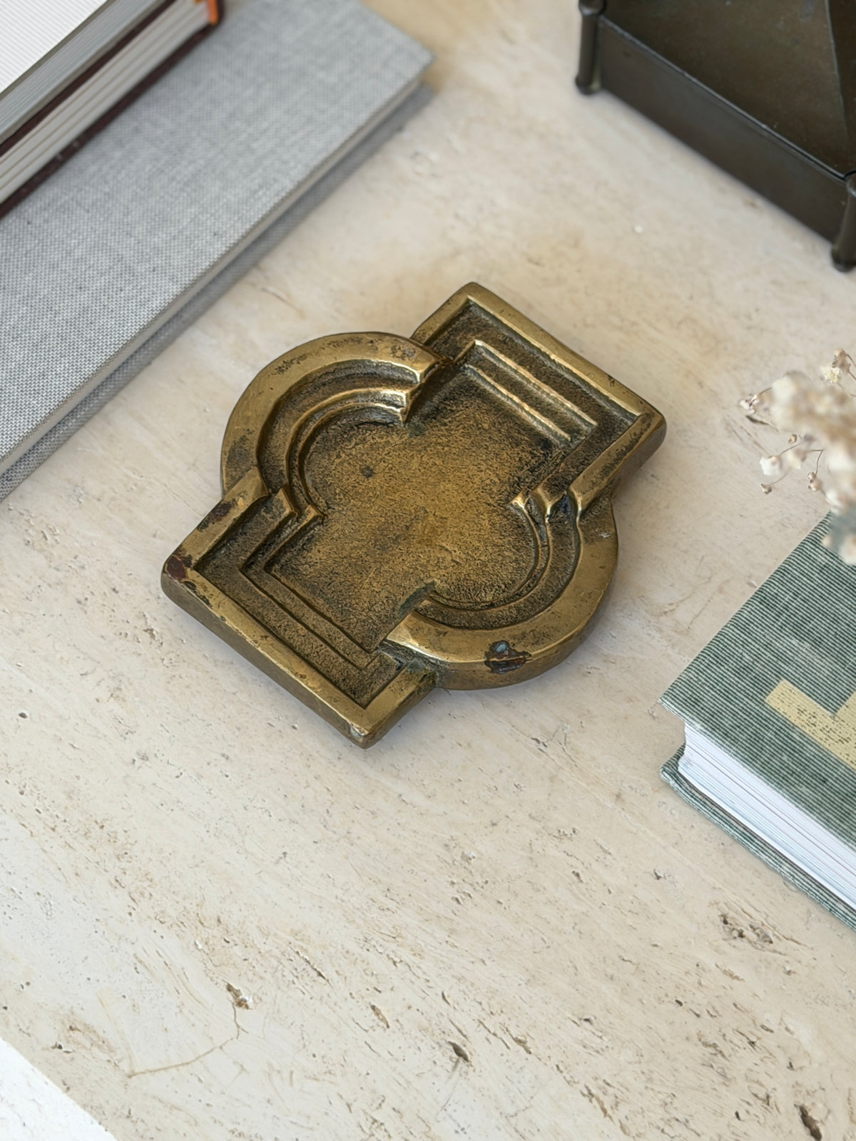 Side perspective view of vintage patinated metal catchall dish styled on executive travertine desk