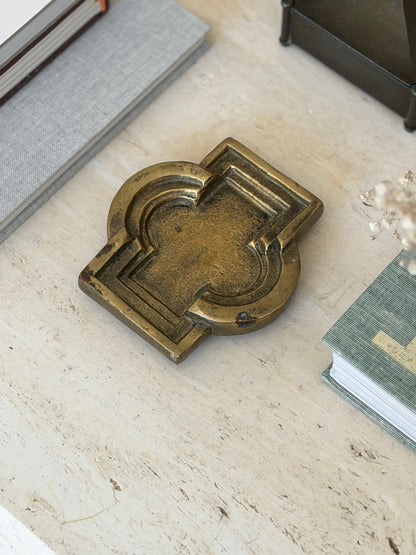 Side perspective view of vintage patinated metal catchall dish styled on executive travertine desk