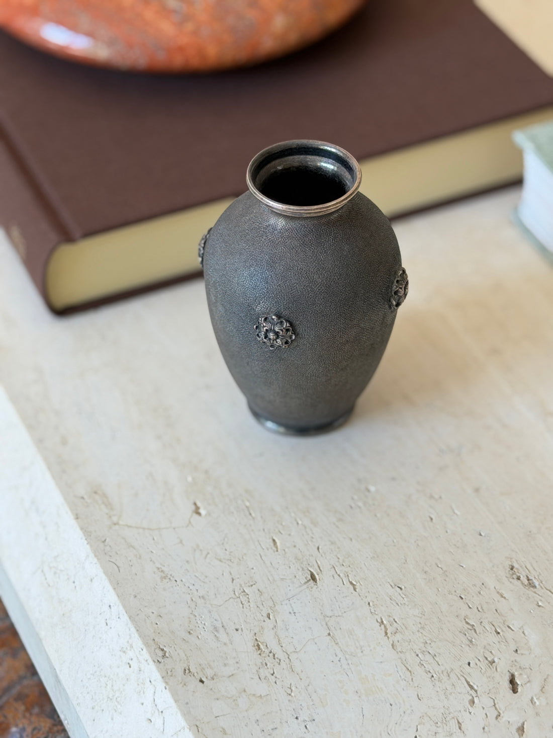 Buccellati textured vase displayed on a stone table with a marble bowl nearby