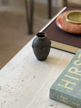 Buccellati vase near a table edge with chair legs blurred in the background