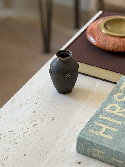 Buccellati vase near a table edge with chair legs blurred in the background