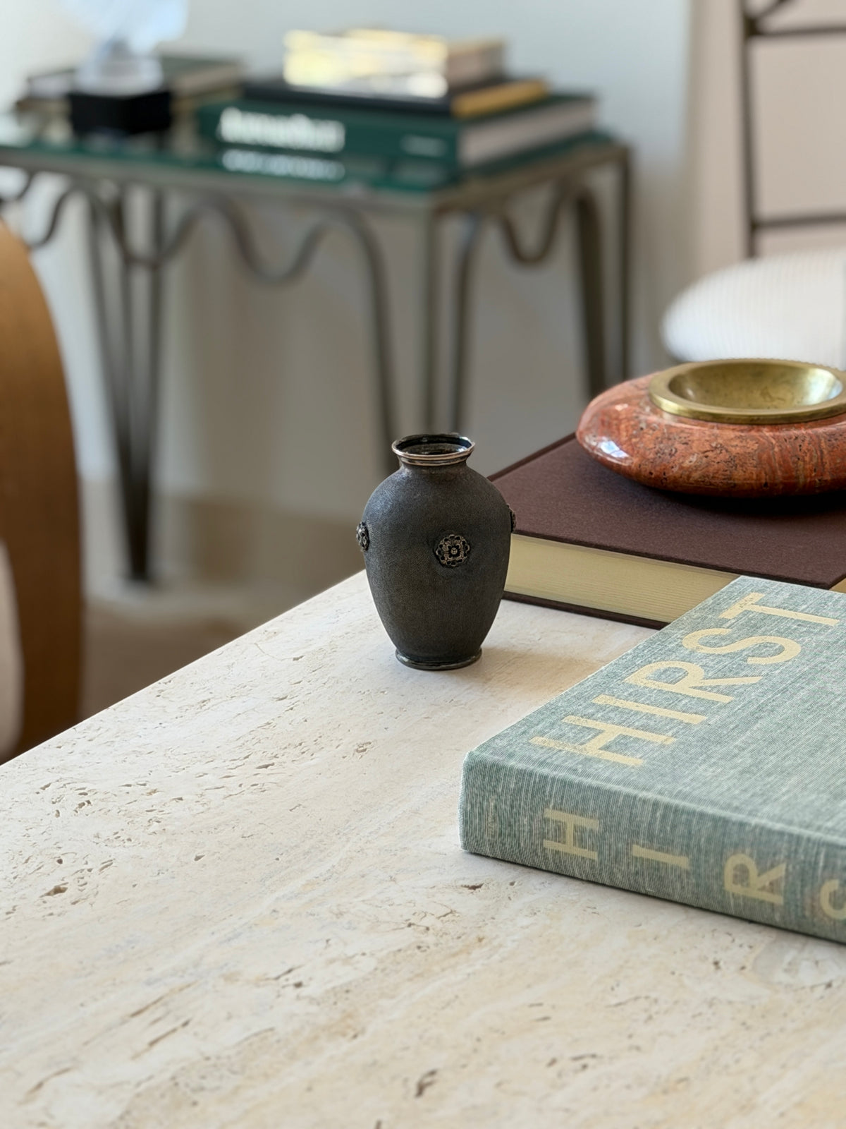 Buccellati vase styled on a console table with seating in the background