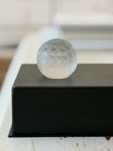 Eye-level front view of Cartier frosted glass golf ball desk accessory on black pedestal display box