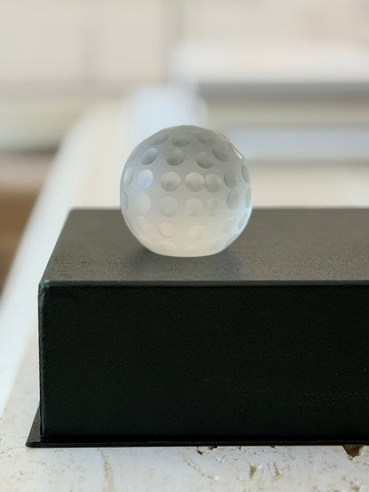 Eye-level front view of Cartier frosted glass golf ball desk accessory on black pedestal display box