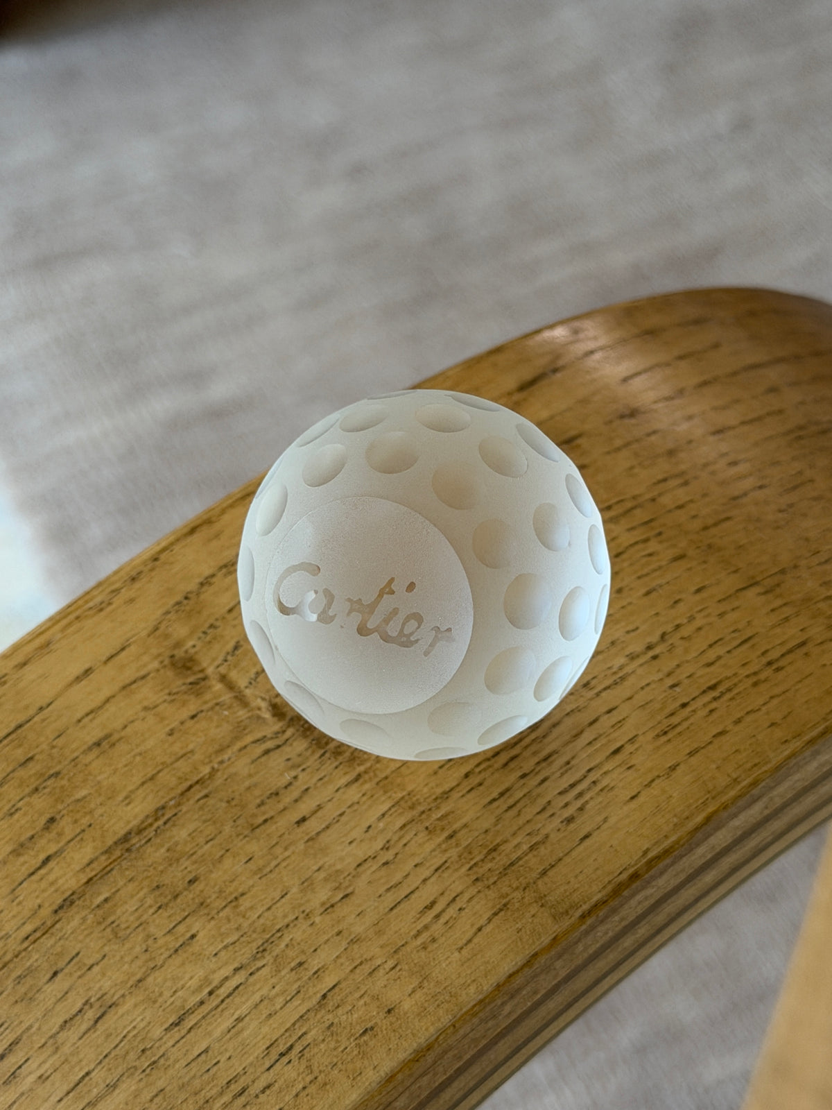 Close-up view highlighting etched Cartier signature on underside of frosted crystal golf ball paperweight
