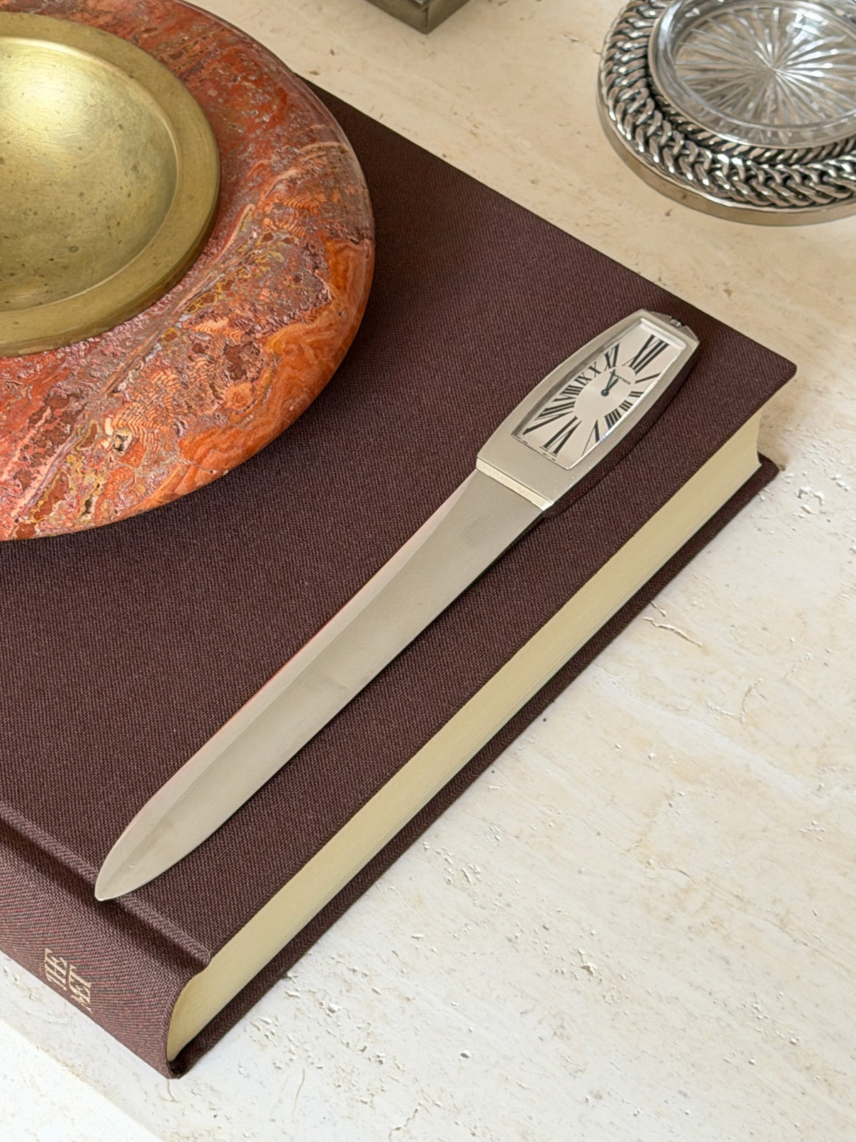 Full-length view of the piece on the book, with the stone bowl and woven coaster visible nearby