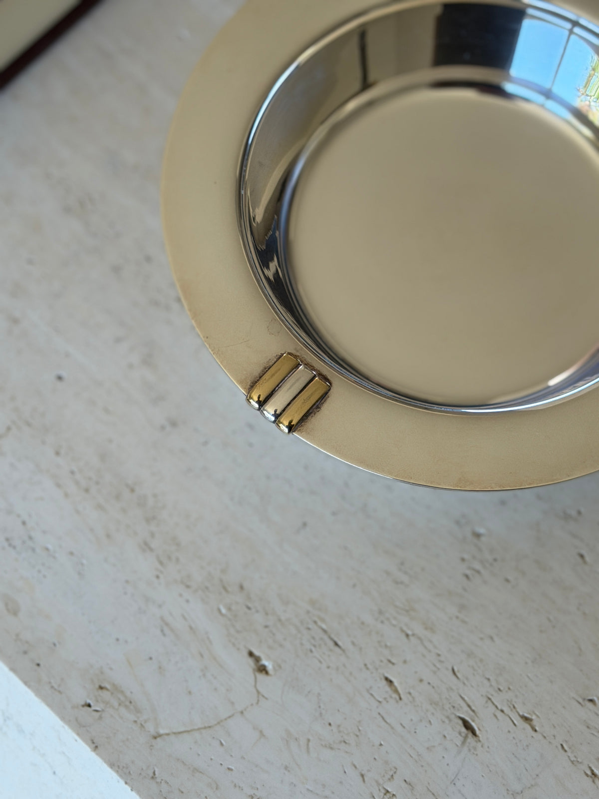 Close detail of the Trinity motif on the coaster rim, two yellow gold toned bars flanking a white silver bar