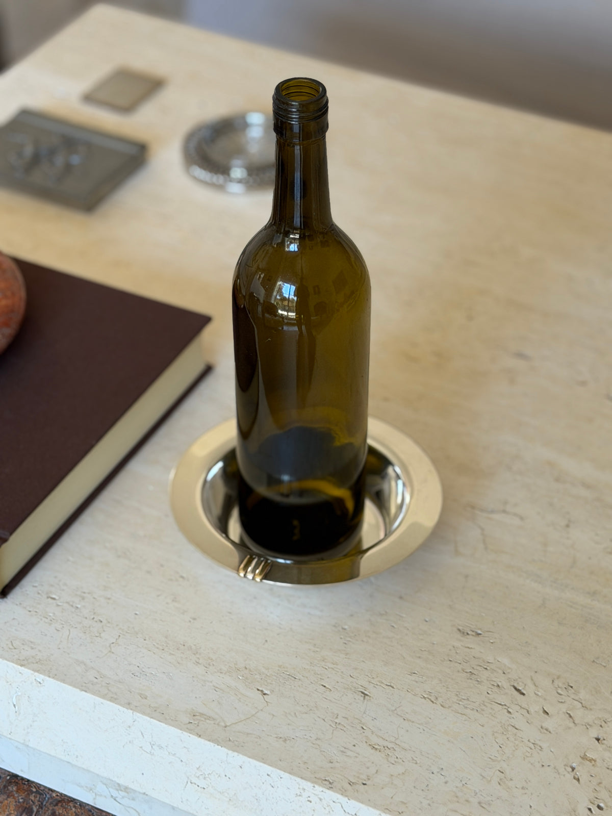 High angle view of a wine bottle standing in the Cartier Trinity coaster, the tricolor bars visible at the rim