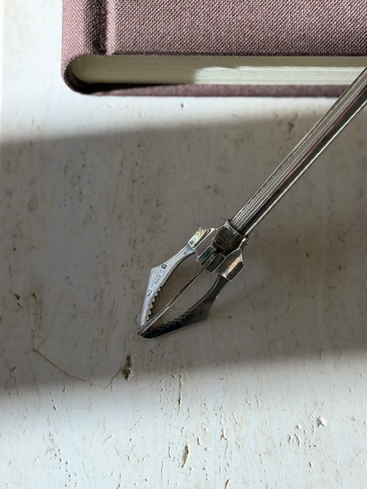 Close up of the serrated jaws stamped Christofle France with small hallmarks, the engine turned shaft above