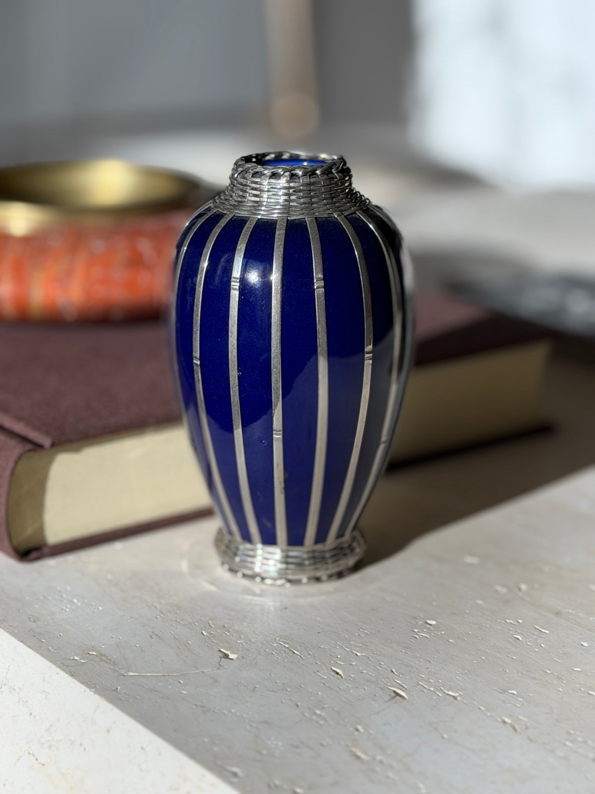 Close eye level view of the cobalt vase, slender vertical silver straps with bamboo style nodes and a basket weave collar