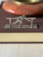 Knife rest of an athlete in a long lunge gripping the rail, set on a brown book before a red stone ashtray