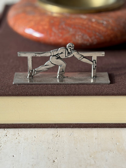 Knife rest of an athlete in a long lunge gripping the rail, set on a brown book before a red stone ashtray