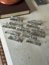 High angle view of the sporting knife rests near a brown book, showing boxers, a fencer, a race car, a motorcyclist, a jockey pair and a draped dancer