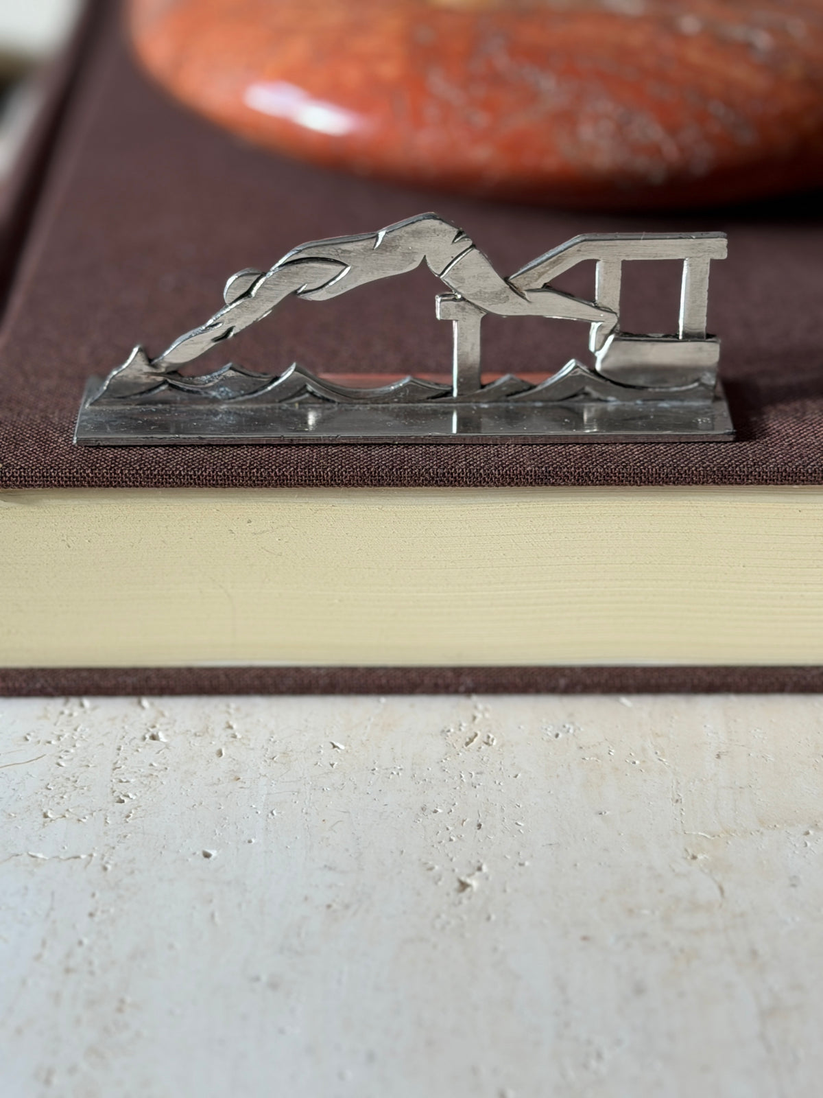 Swimmer knife rest on a brown book, a diver launching from a starting block over stylized waves