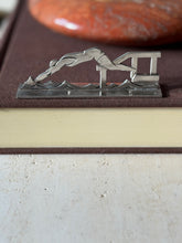 Swimmer knife rest on a brown book, a diver launching from a starting block over stylized waves