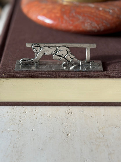 Rugby knife rest on a brown book, a capped player diving to ground the ball beneath the rail
