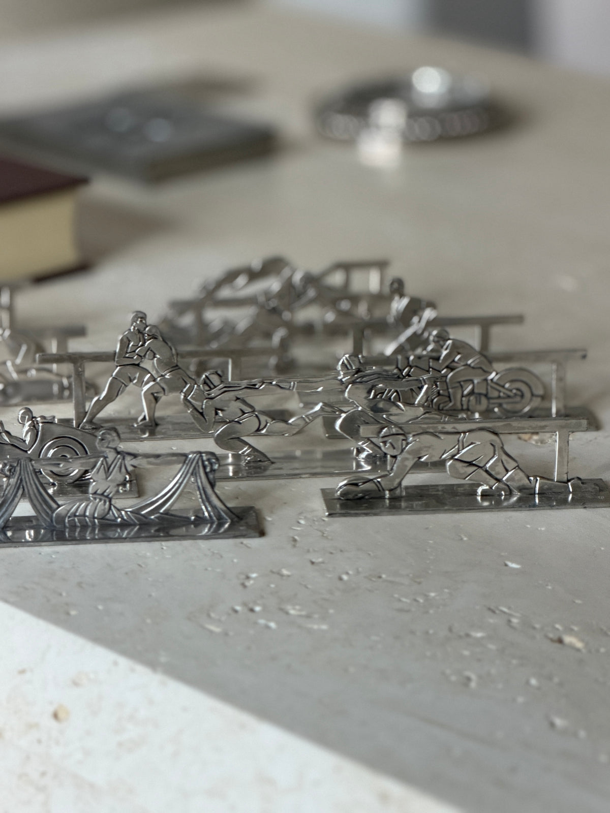 Eye level view of the silver plate knife rests on travertine, a rugby player, motorcyclist and skating pair in stylized relief