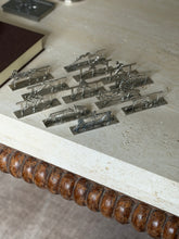 The set of twelve Art Deco knife rests on the corner of a travertine coffee table above its bobbin turned wood apron