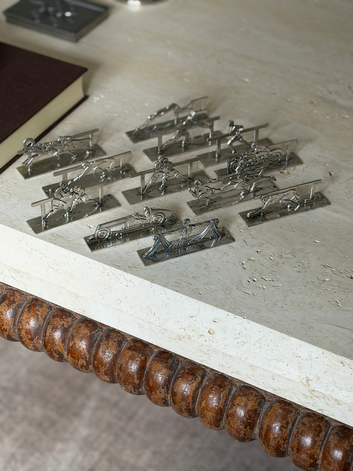 The set of twelve Art Deco knife rests on the corner of a travertine coffee table above its bobbin turned wood apron