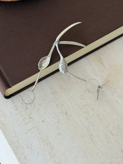 Flamingo tongs opened on a brown book, revealing the hidden spoon bowl inside the bill and the separate bird foot stand