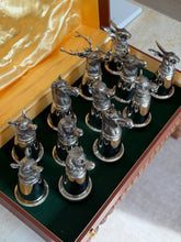 Overhead view of the open Gucci fitted display box, gold satin lid stamped Gucci, with the twelve silver stirrup cups arranged in the green baize lined base
