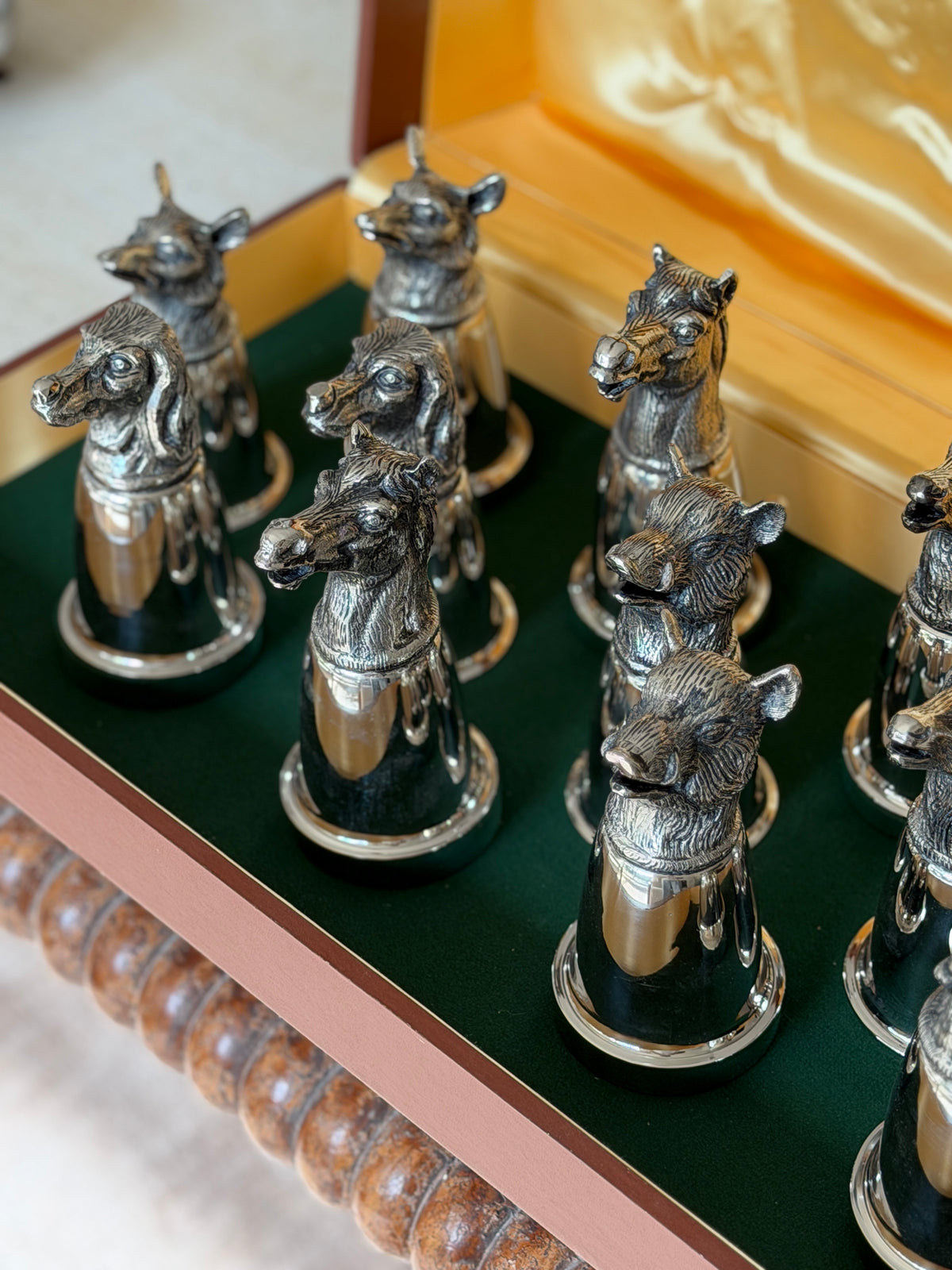 Close-up of a group of horse and boar head cups, showing the detailed modeling of the manes and bristles against the green baize lining