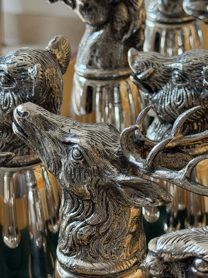Extreme close-up of a single stag head cup, showing the finely engraved fur texture, open mouth, and curling antlers