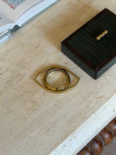 Hermes gilt eye magnifier on a travertine table next to a dark lacquered box with a brass handle