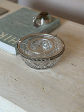 Hermes caviar service displayed on a travertine surface with a book nearby