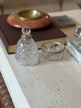Hermes crystal bottle and matching bowl displayed together on a leather book