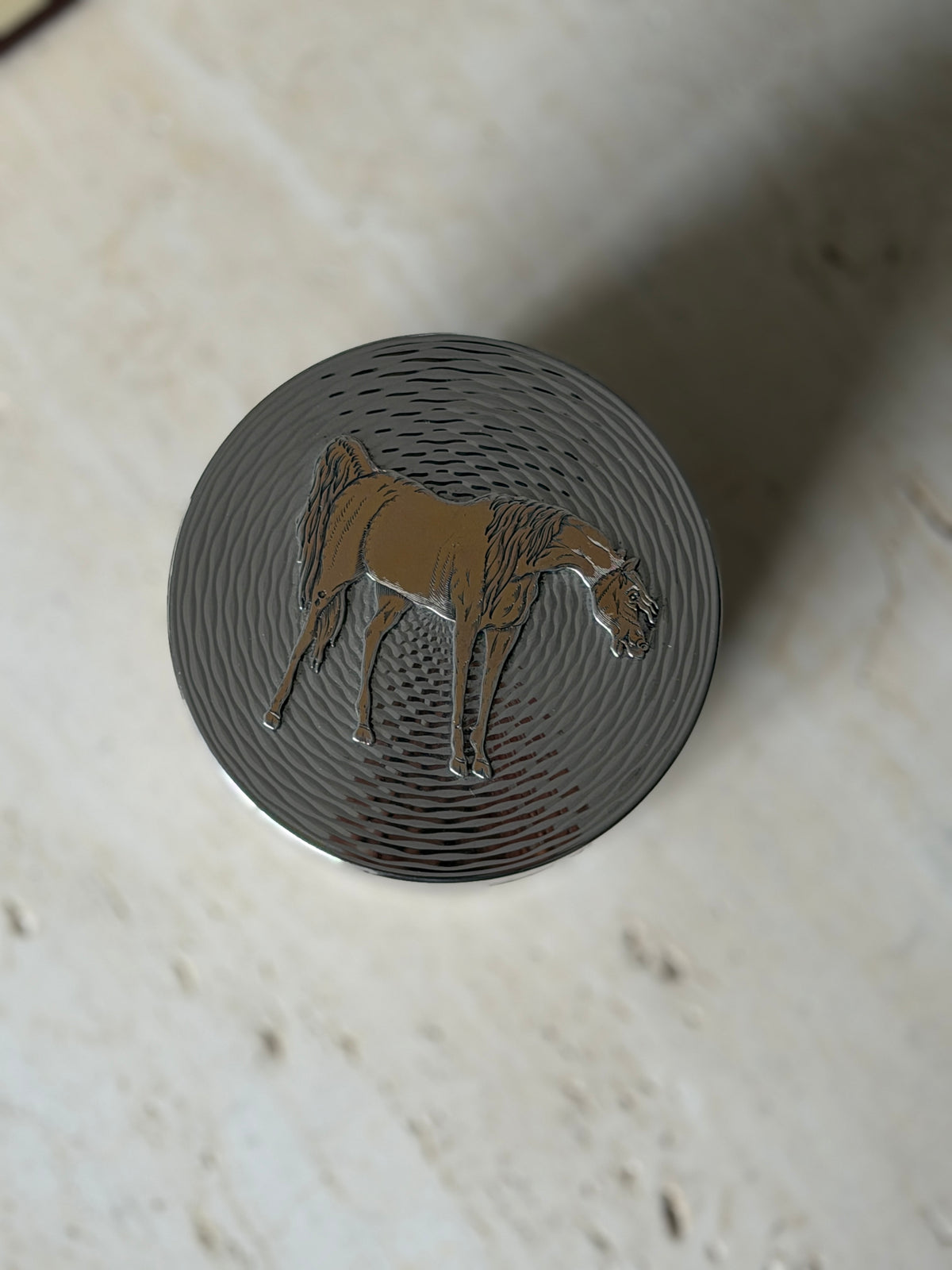 Side view of the Hermes solid silver box, rows of rippling engine turned lines wrapping the body below the fitted lid