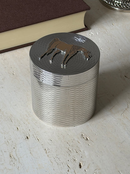 Angled close view of the Hermes box, the gilt horse in raised relief above the textured lid and wavy engraved sides
