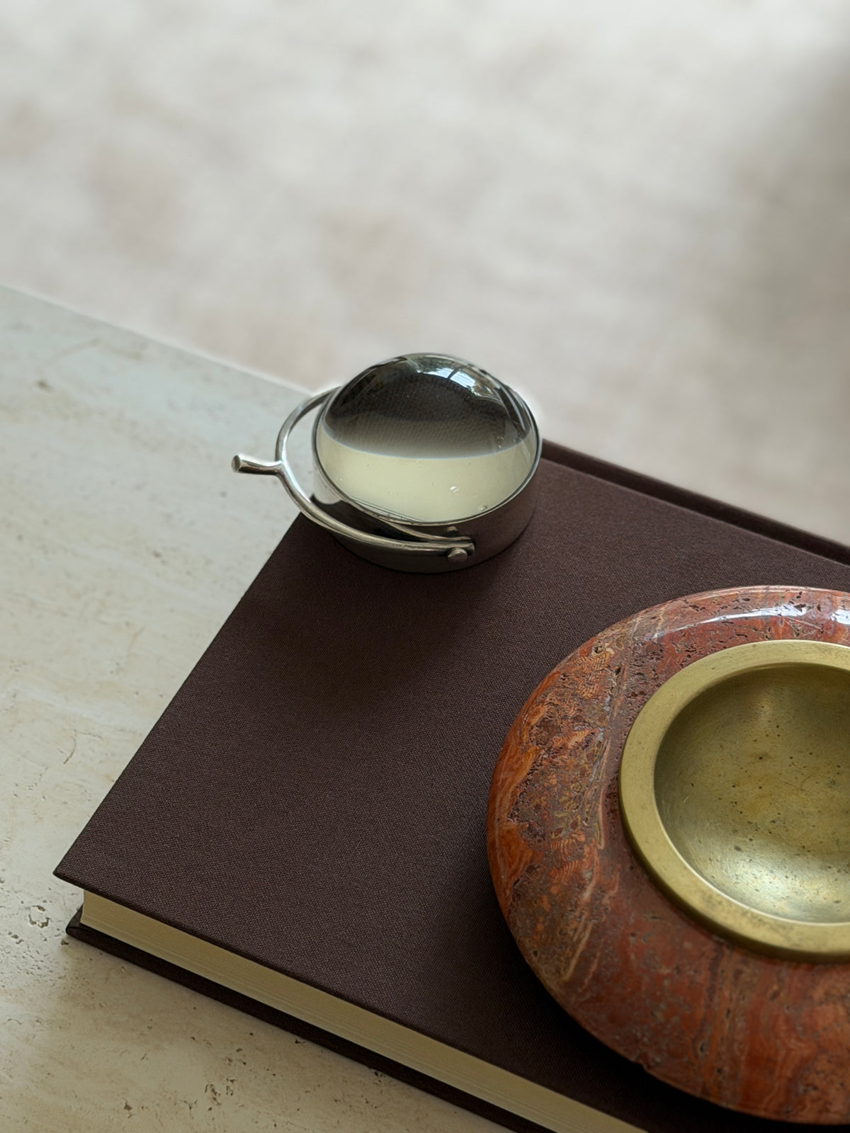 The magnifier on the book beside the orange stone bowl with its brass insert