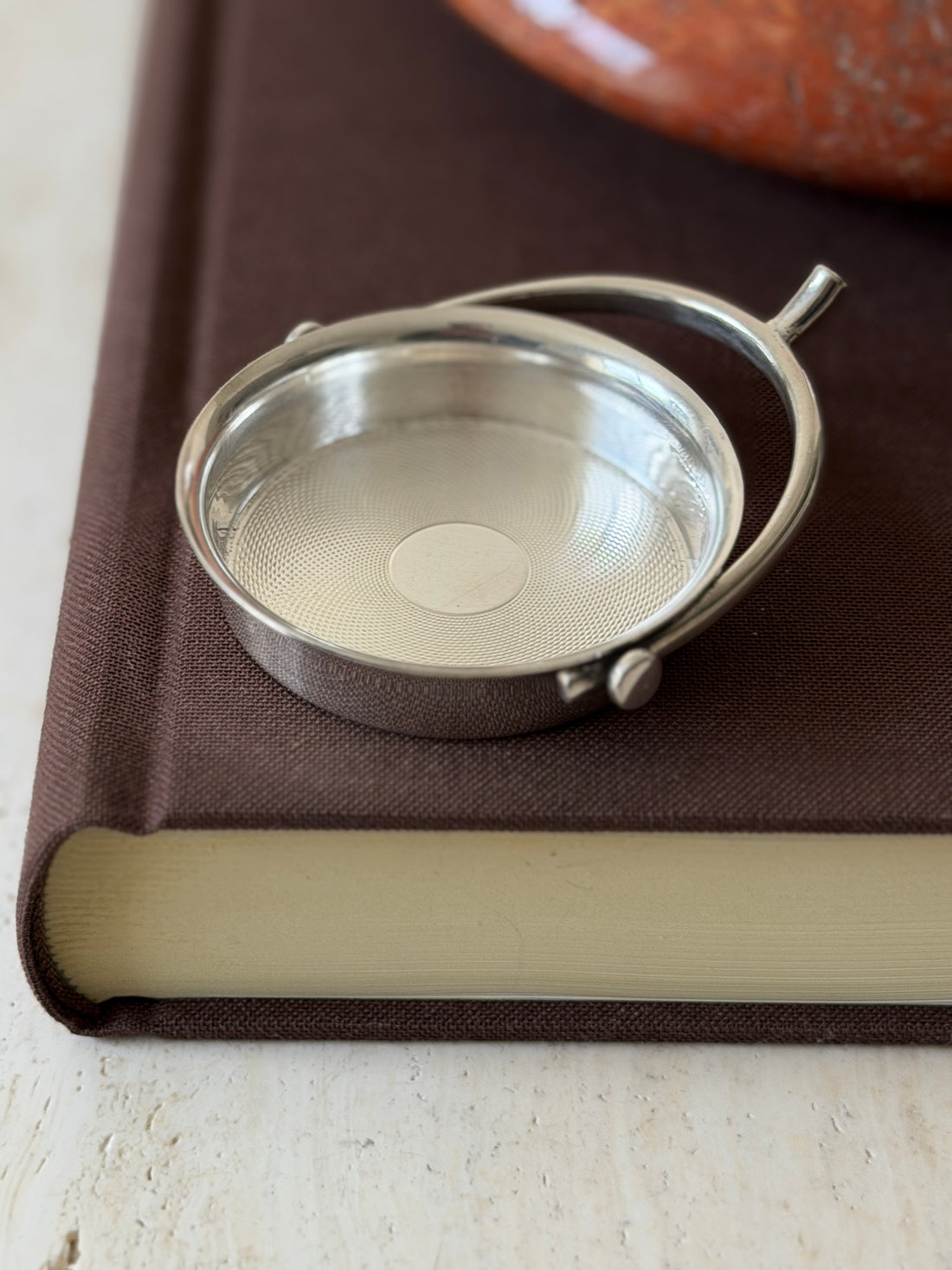Close view of the spur catchall on a book edge, showing the ball end pivot and the shimmering engine turned interior